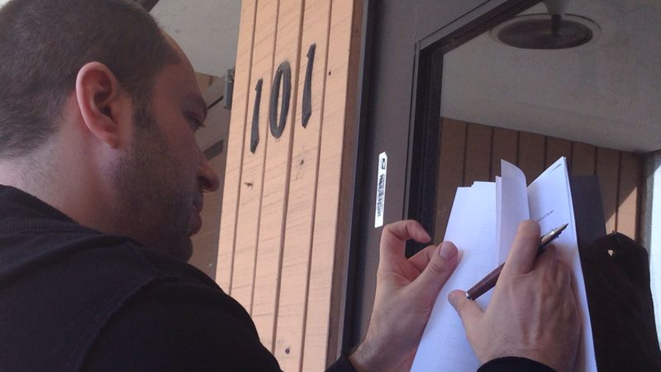 Jan Koum signs the $19 billion Facebook deal paperwork on the door of his old welfare office in Mountain View, Calif. (Photo courtesy of Jan Koum)